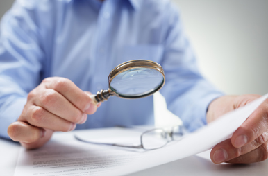 Mann mit Lupe betrachtet ein Schriftstück